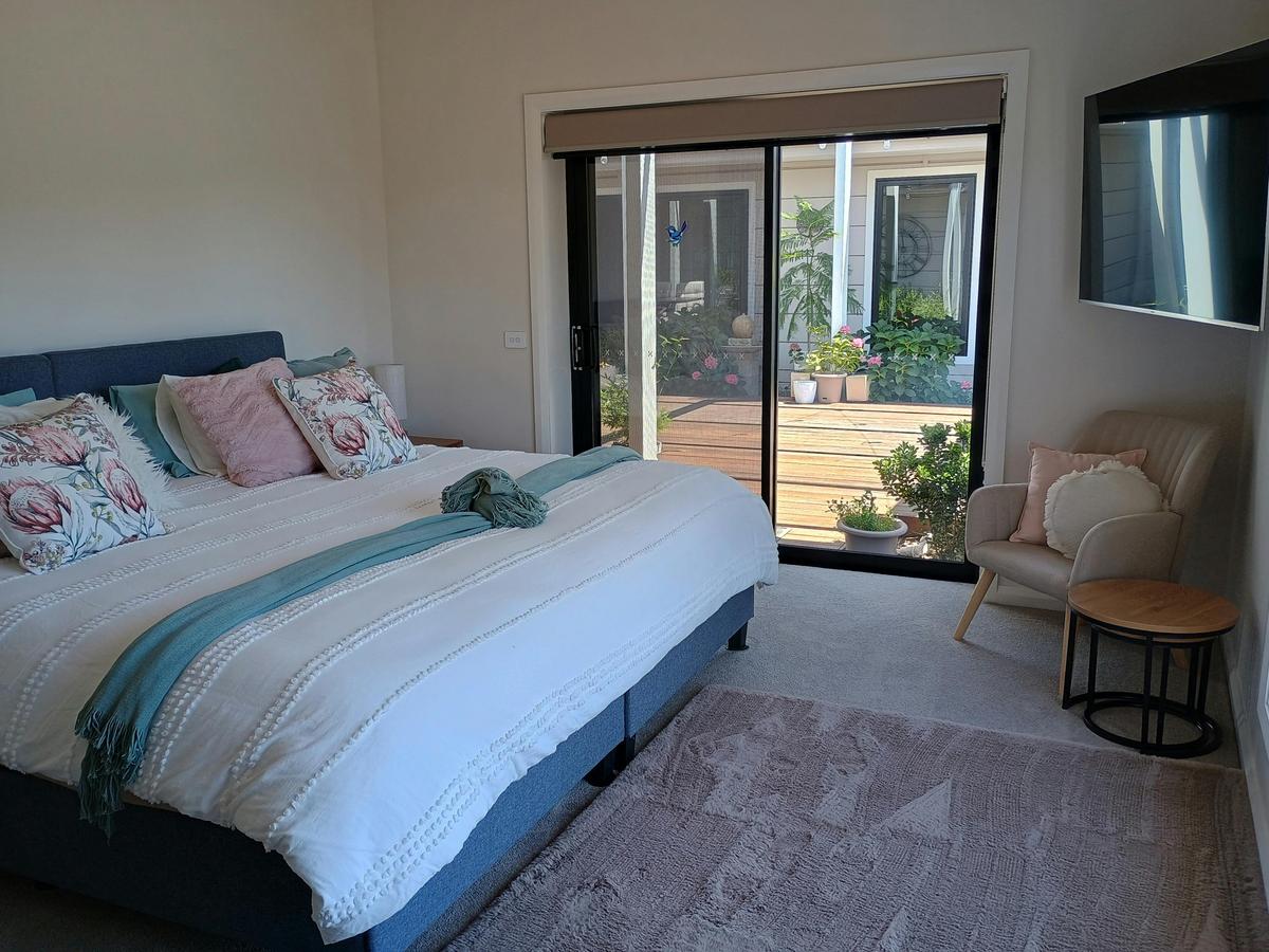 A king sized bed with a large window to the left and a television in front