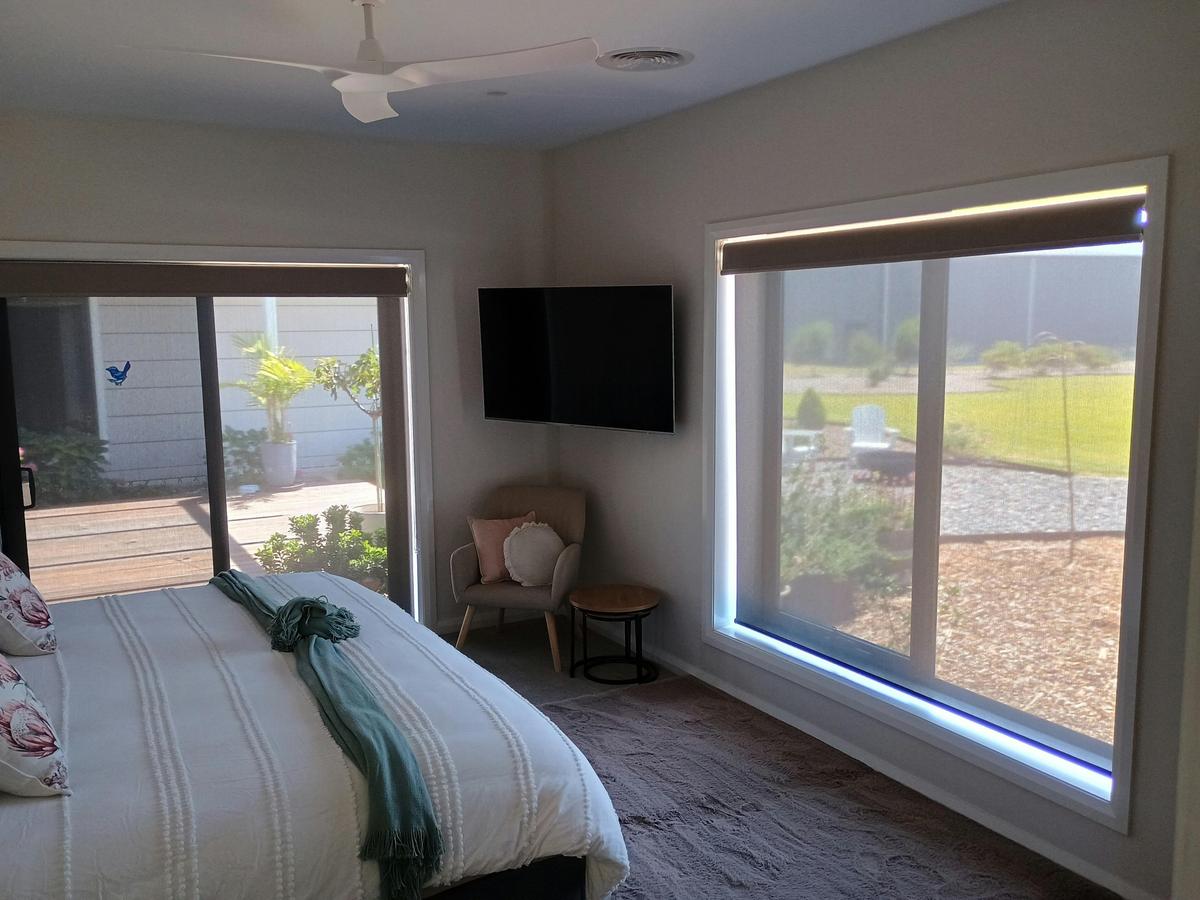 A bedroom with a king sized bed facing a large window looking out to the garden