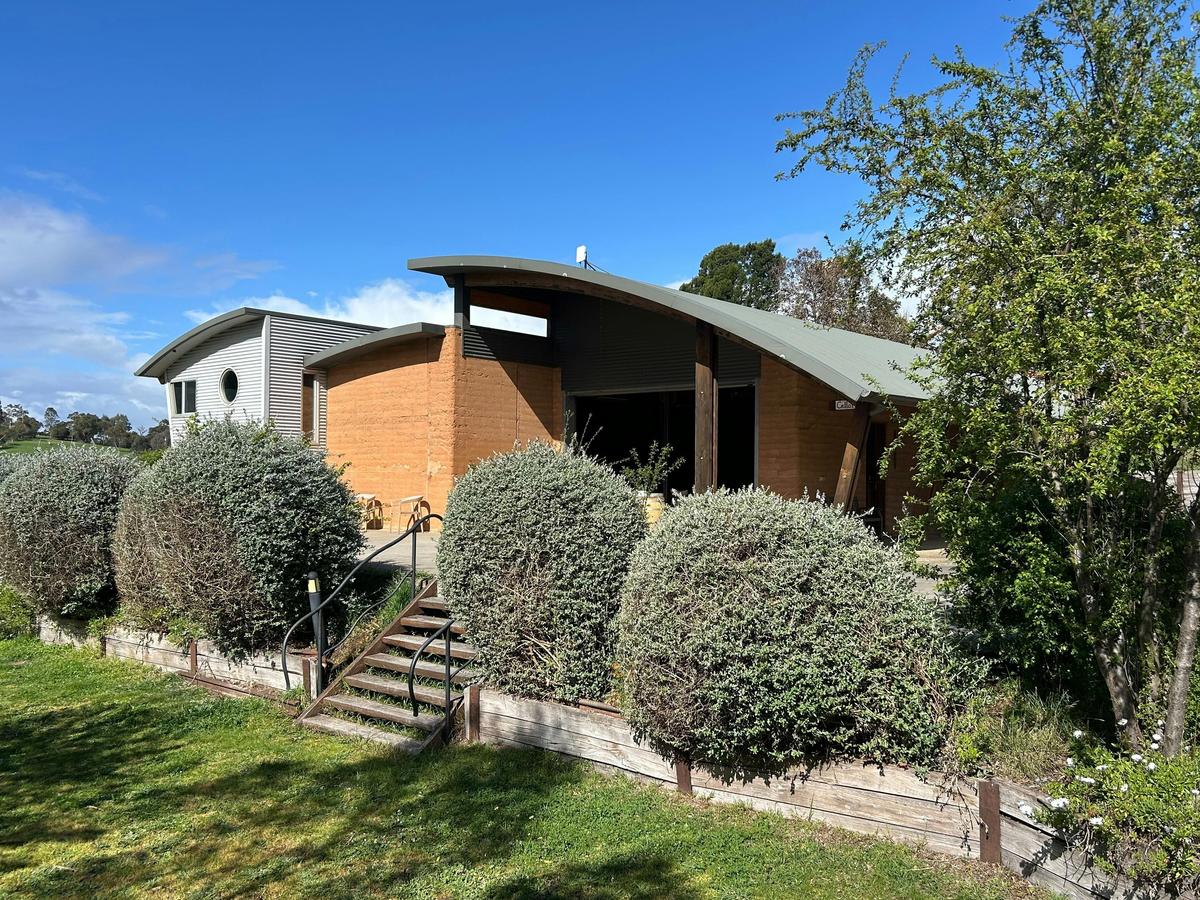 Wedgetail Estate’s rammed earth cellar door, nestled amongst native shrubs