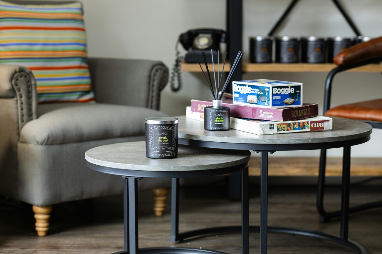 A candle and a reed diffuser on a table with some board games.