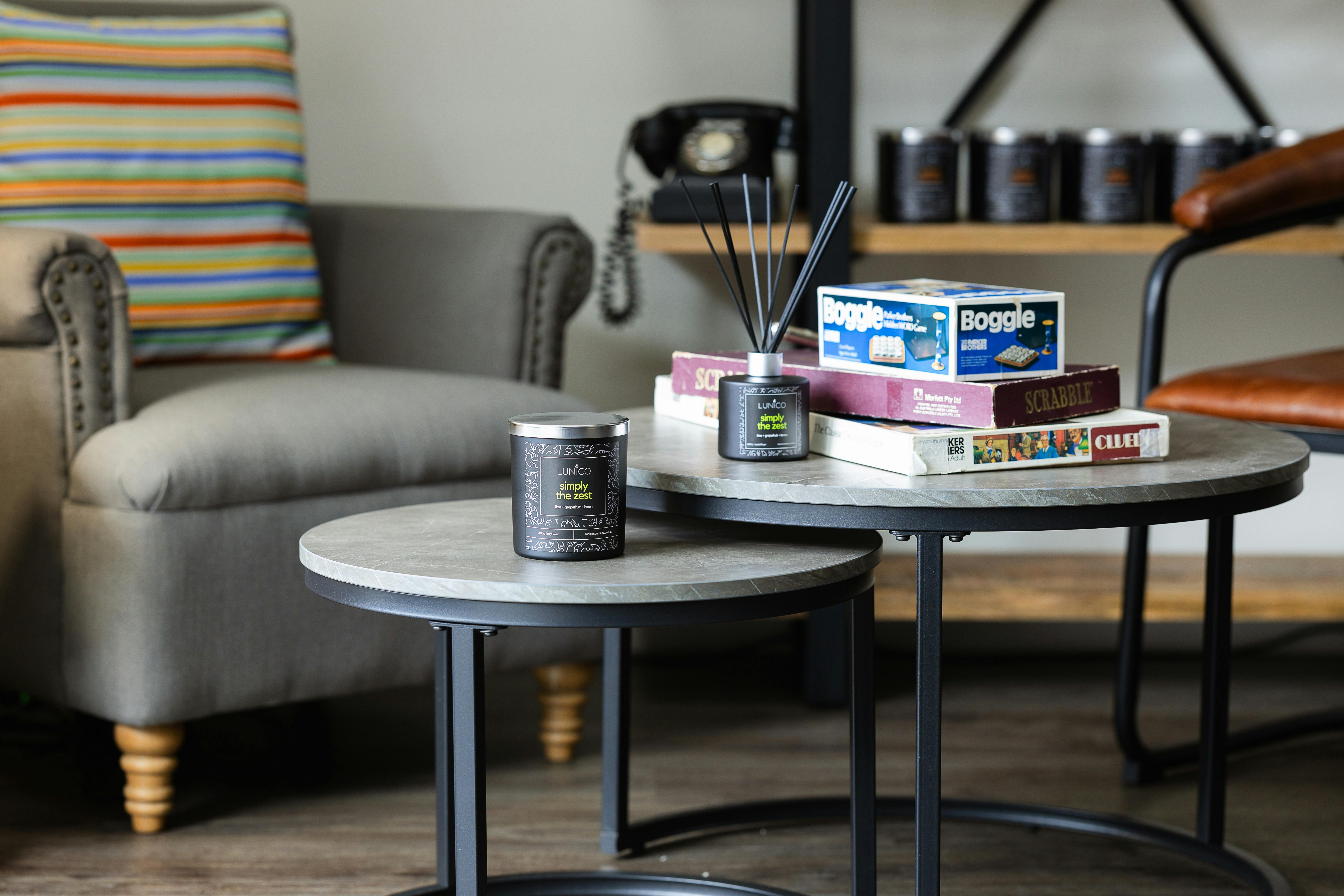 A candle and a reed diffuser on a table with some board games.