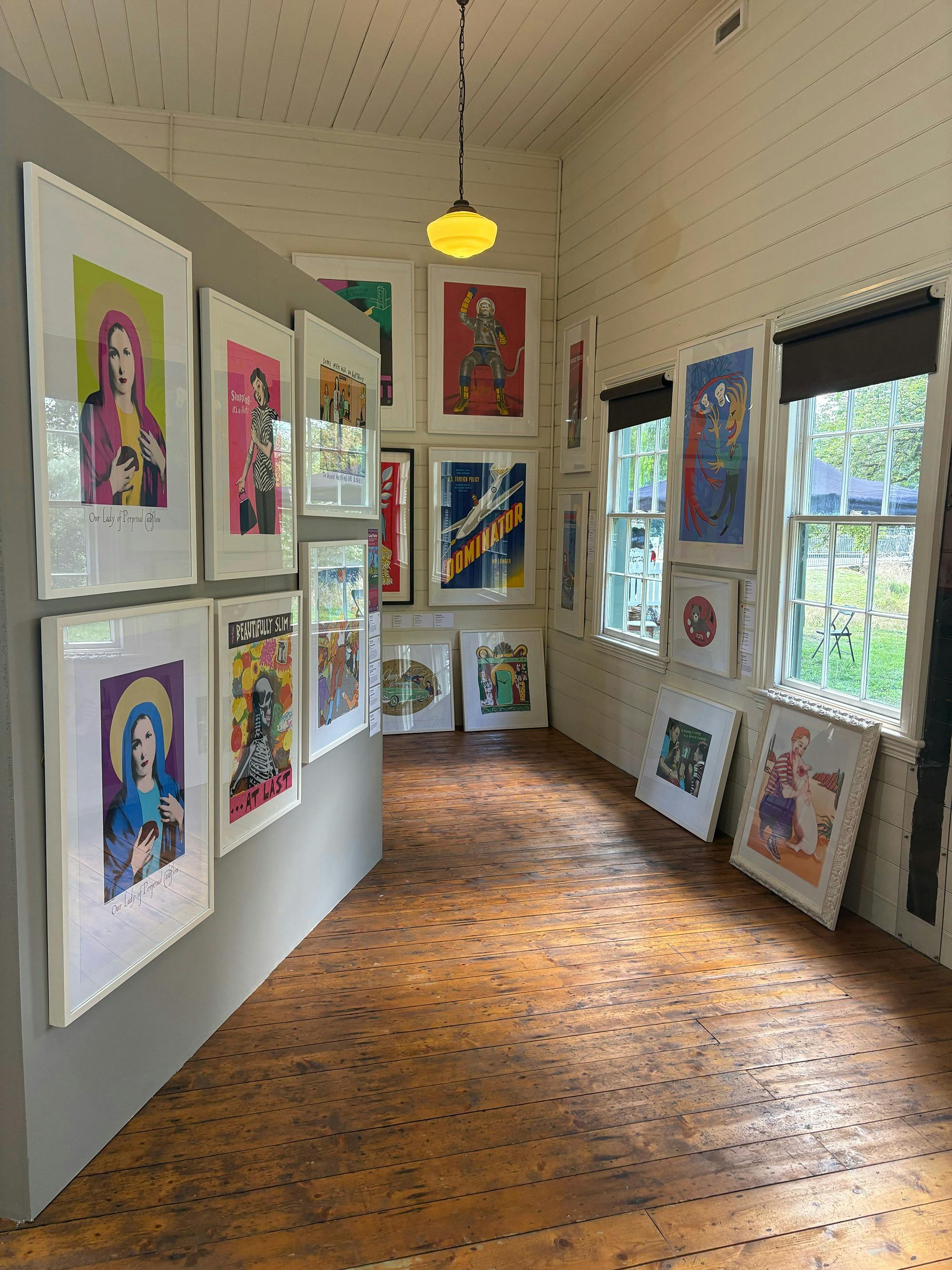 Vibrant screenprints hang salon-style, filling the heritage timber gallery floor to ceiling.