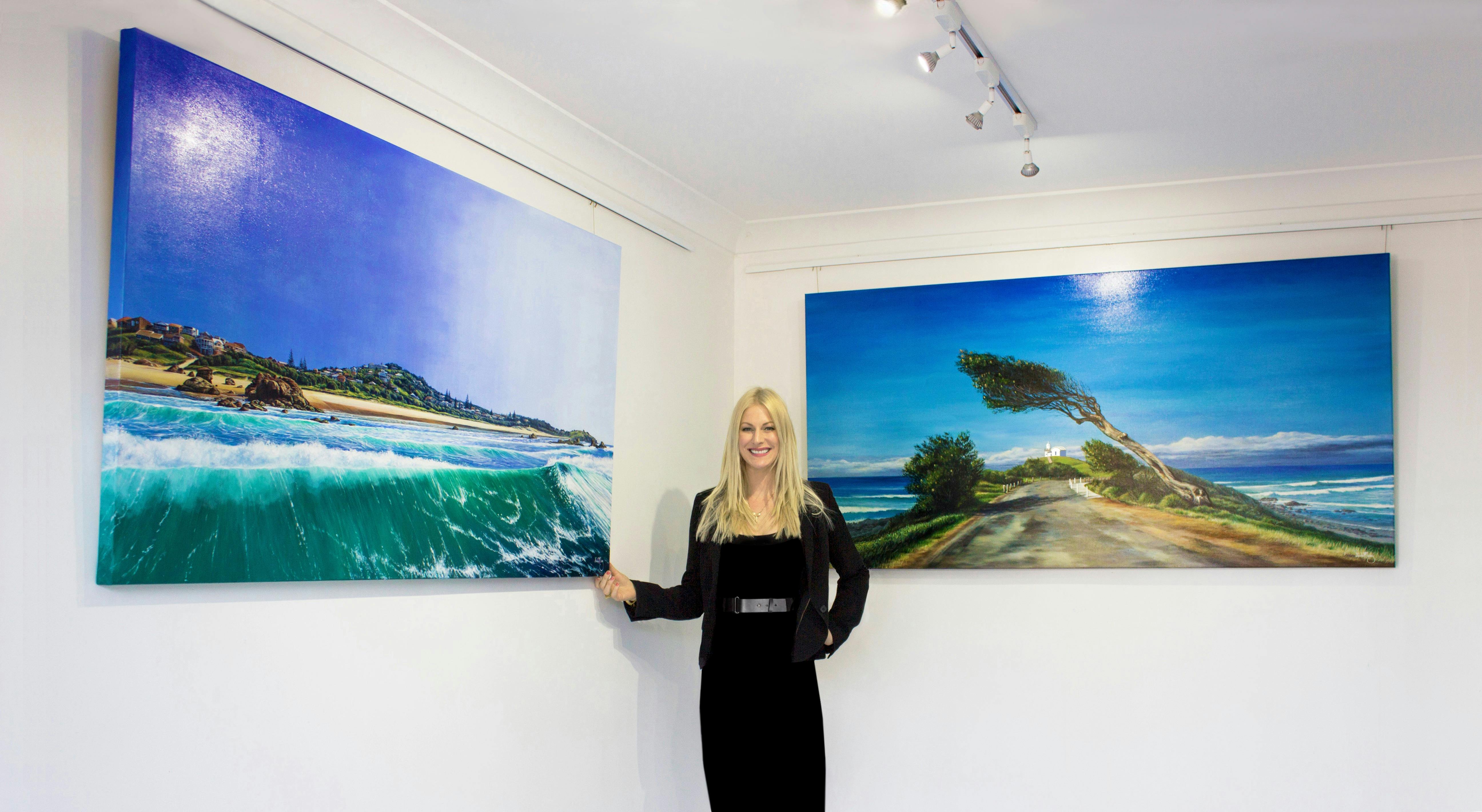 Artist in gallery beside oil paintings