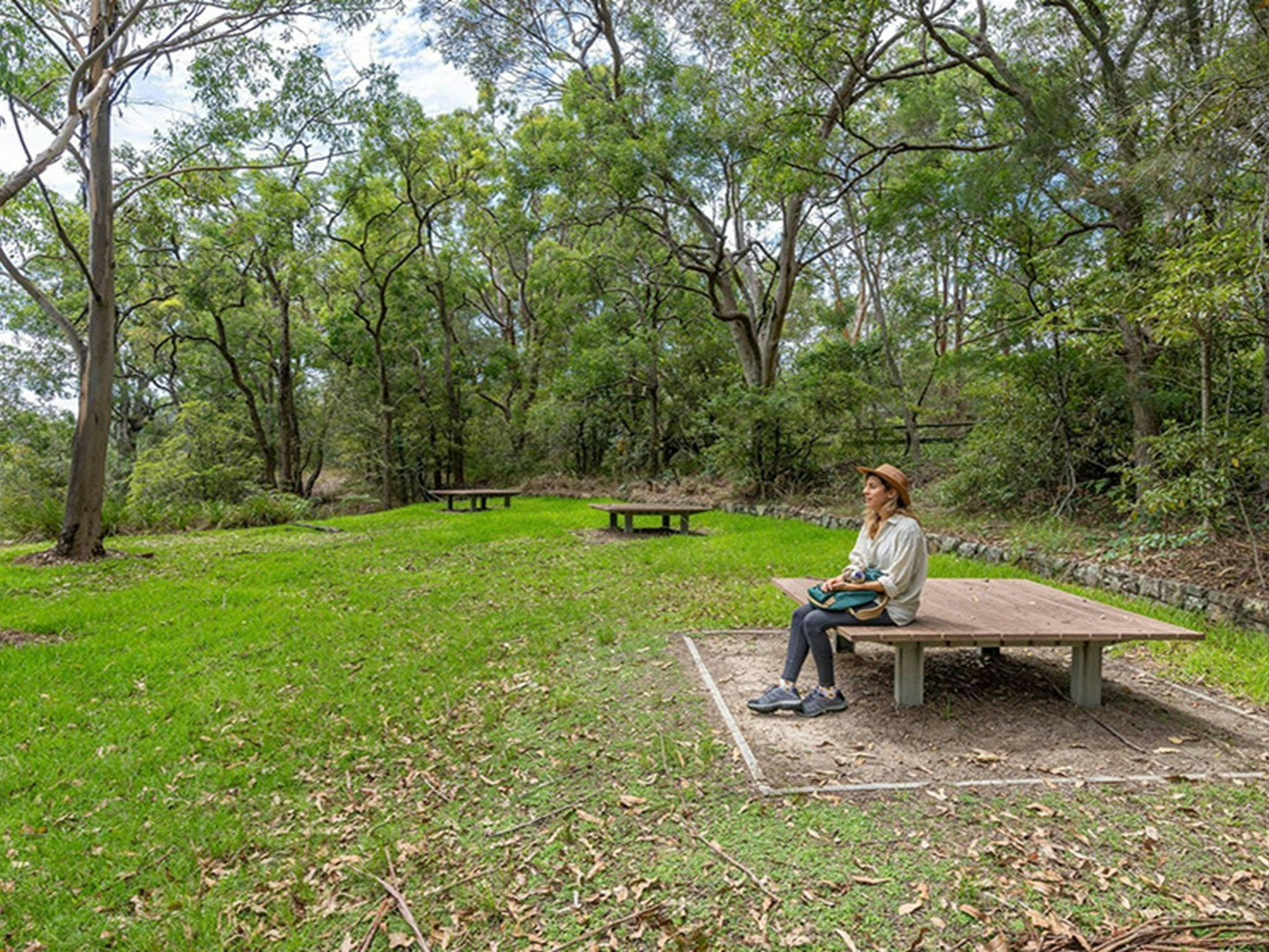 A person sitting on a picnic platform surrounded by bush at Apple Tree picnic area, Ku-ring-gai