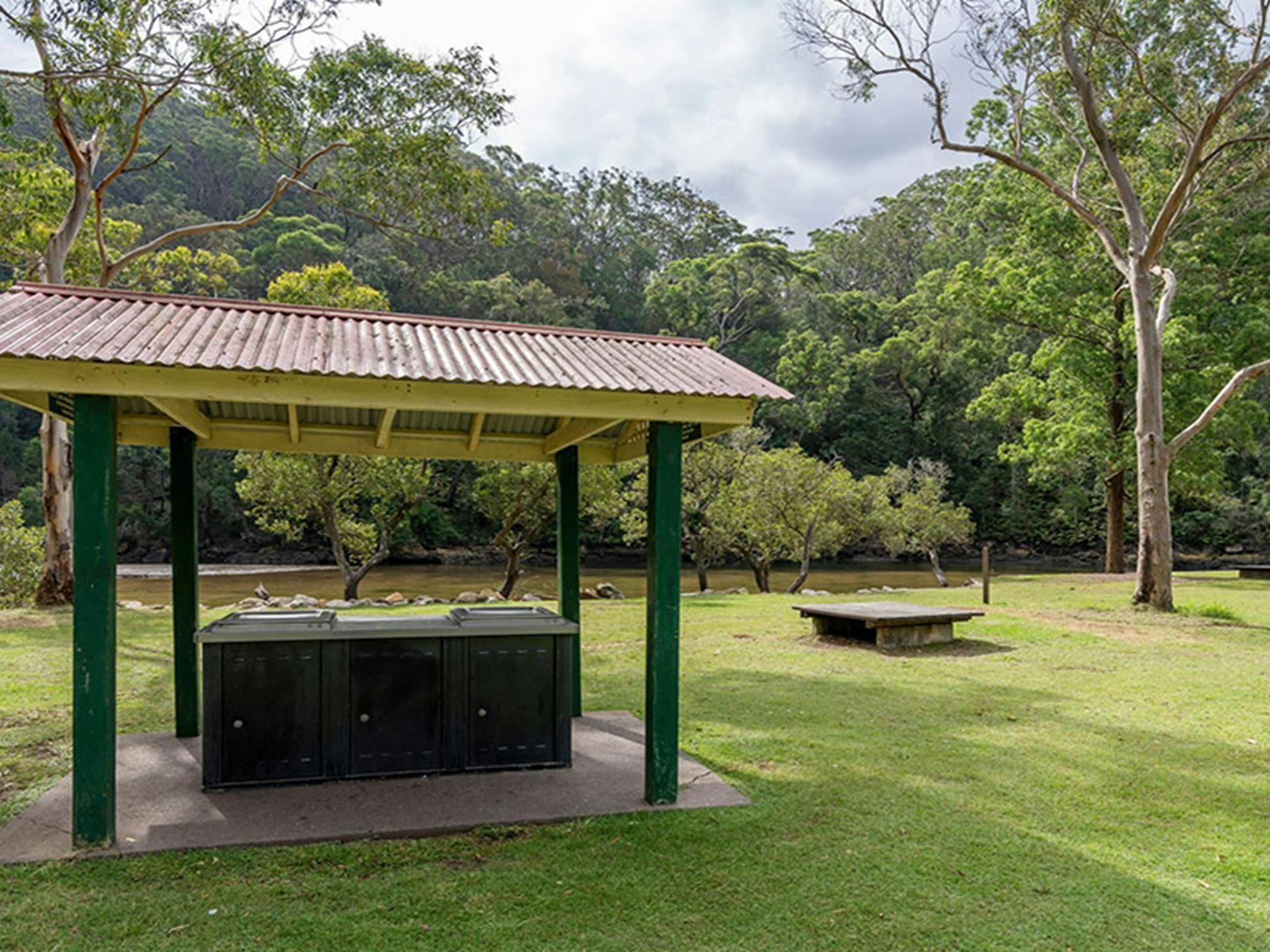 Sheltered barbecues next to a picnic platform on a lawn at Apple Tree picnic area with a creek and
