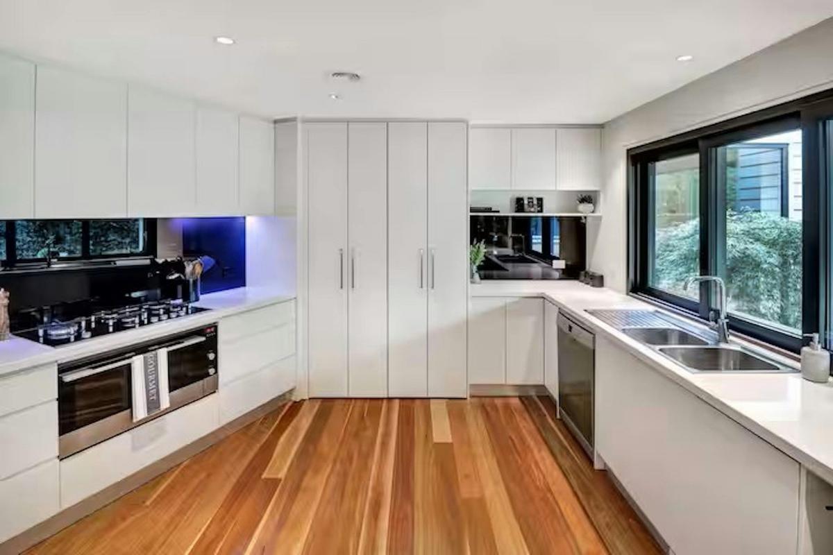 Modern fully equipped kitchen with stone benchtops, quality appliances and servery at Banksia House