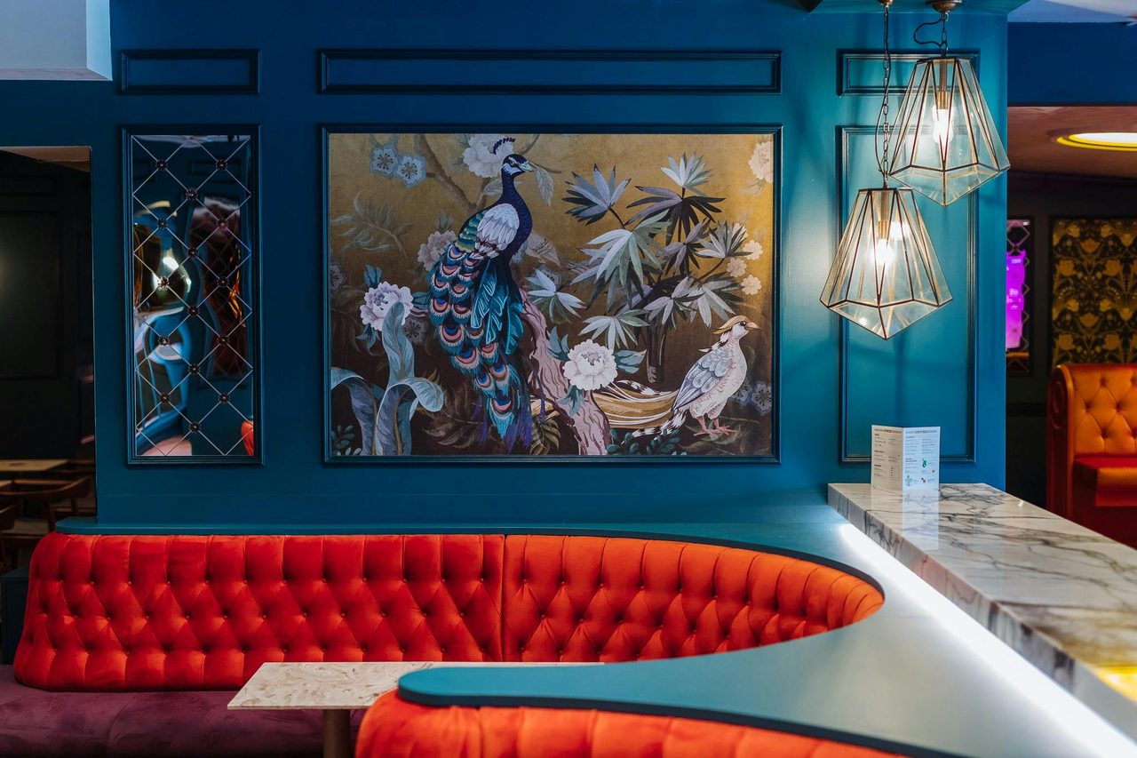 Luxurious red bar booths and blue peacock artwork on wall