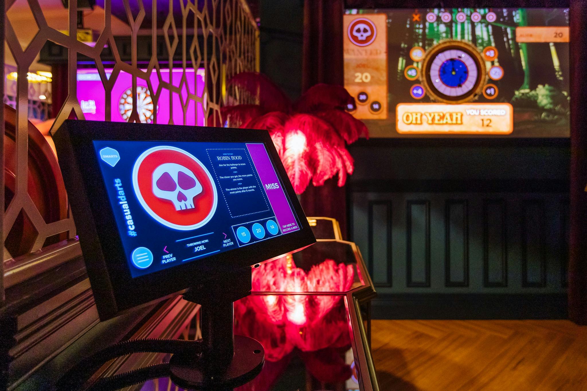 Screen displays a La Di Darts game with a skull on it. Dart board can be seen in the background.