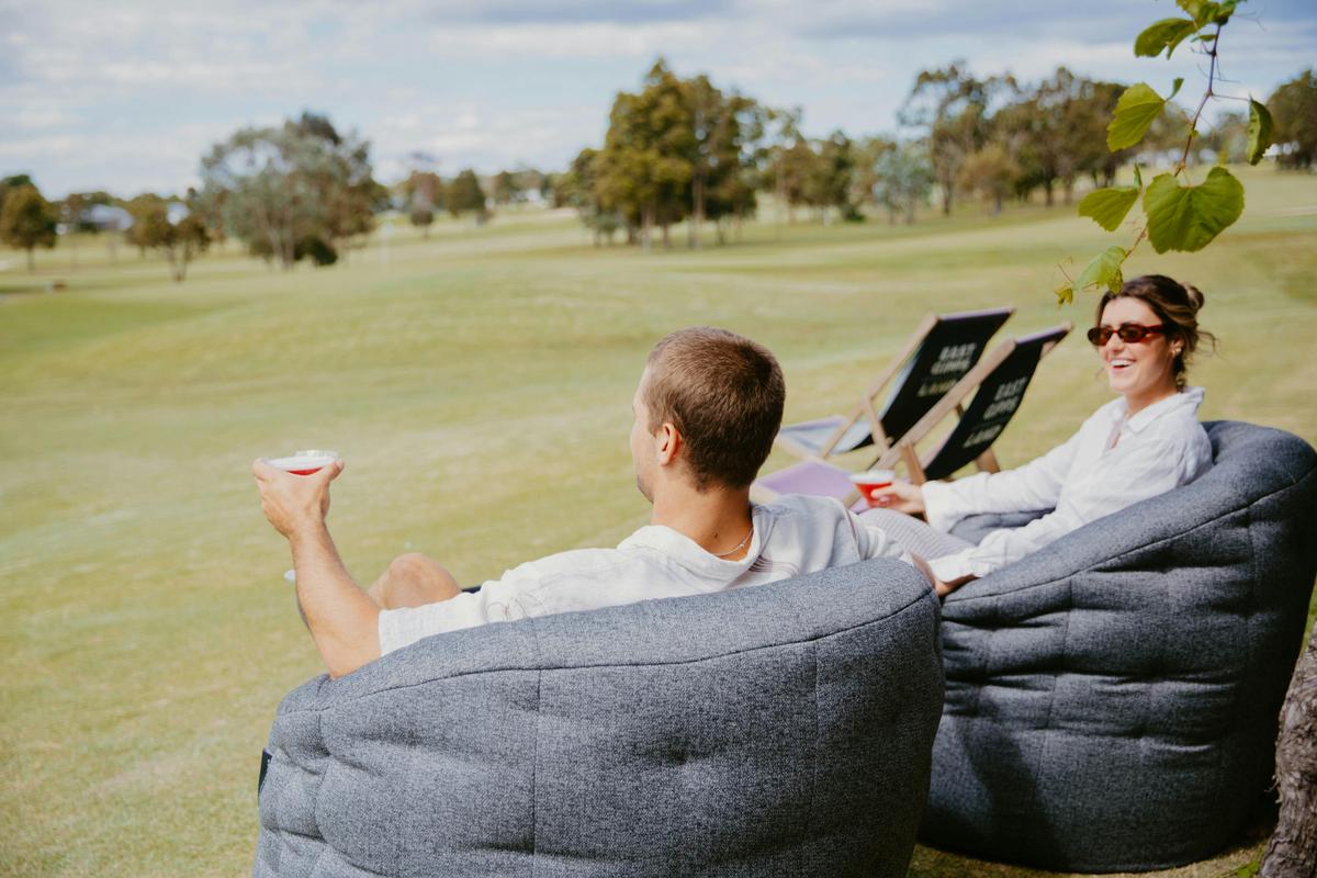 Couple enjoying drinks on outdoor lounges overlooking Golf course