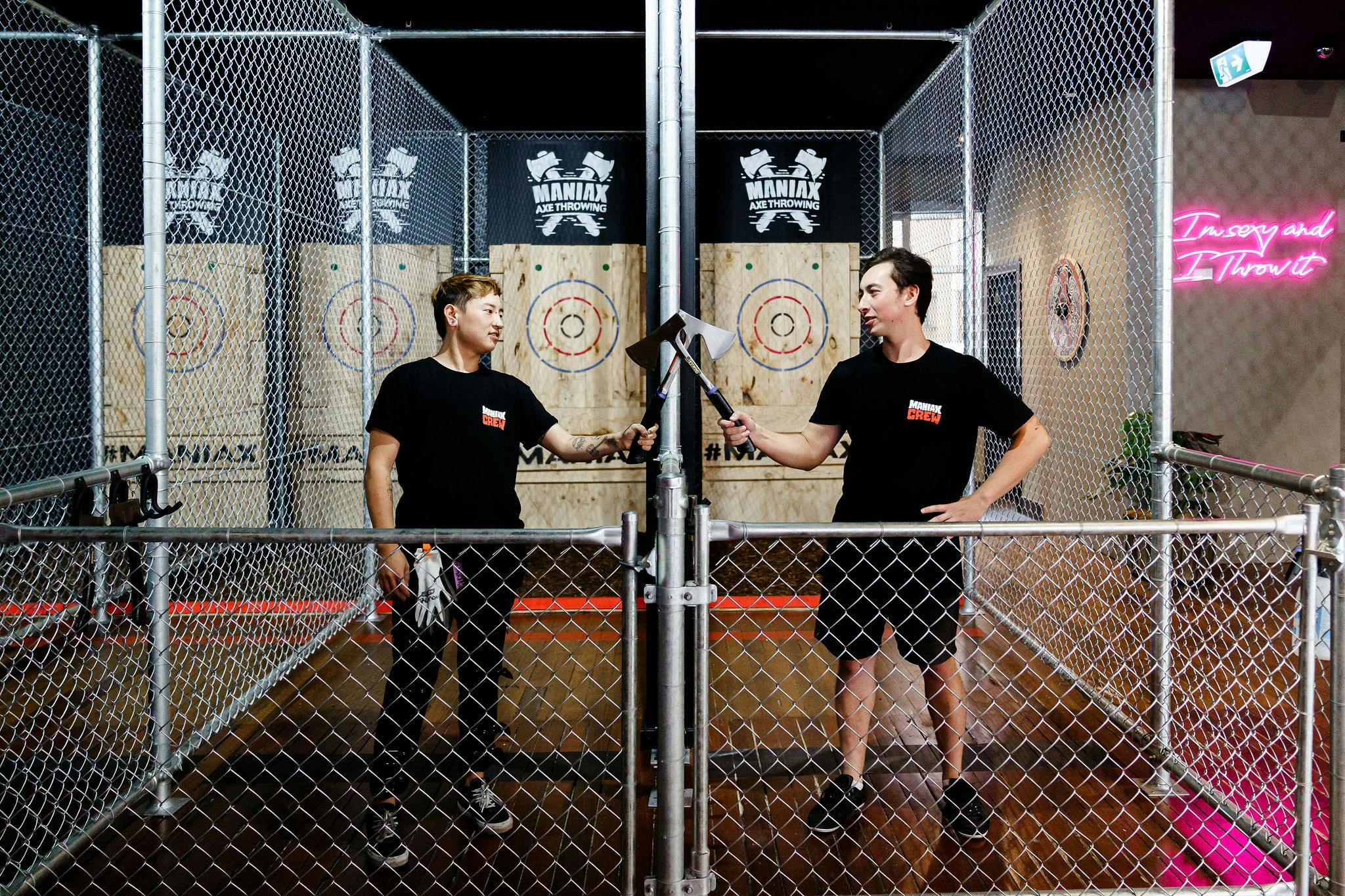 Two MANIAX AXE-perts pose in front of targets touching axes