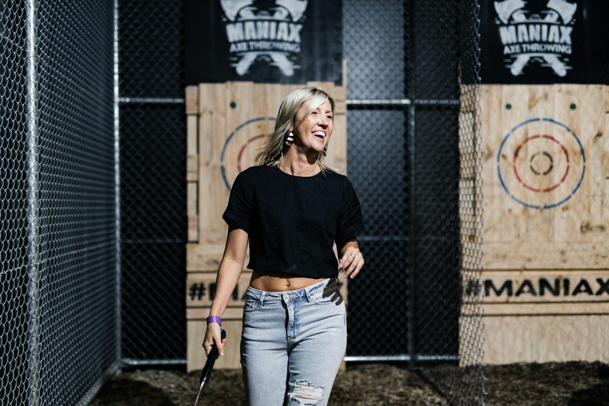 Woman happy holding an axe in front of a target