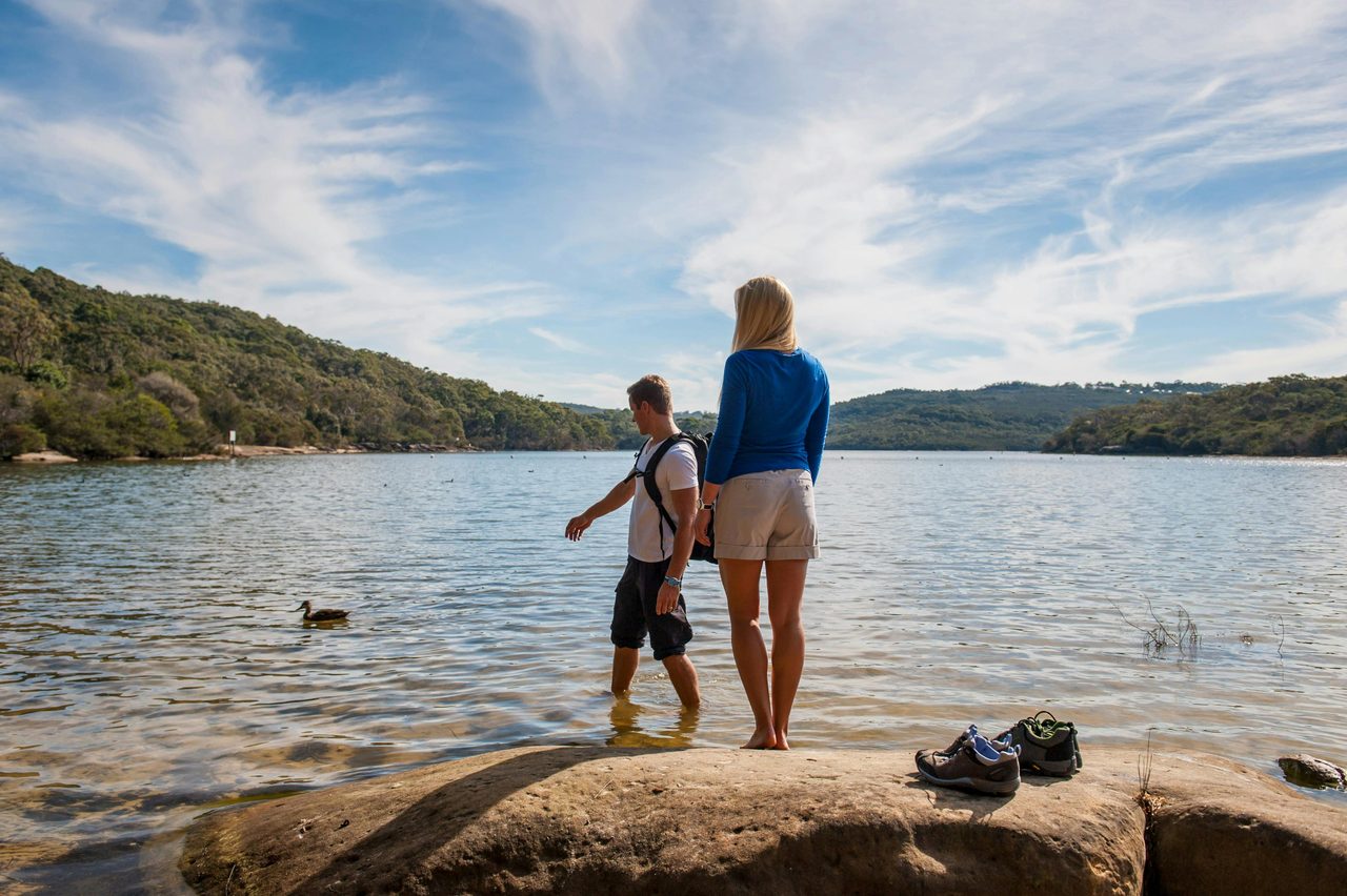 A man and a woman standing on a rock near the Manly Dam