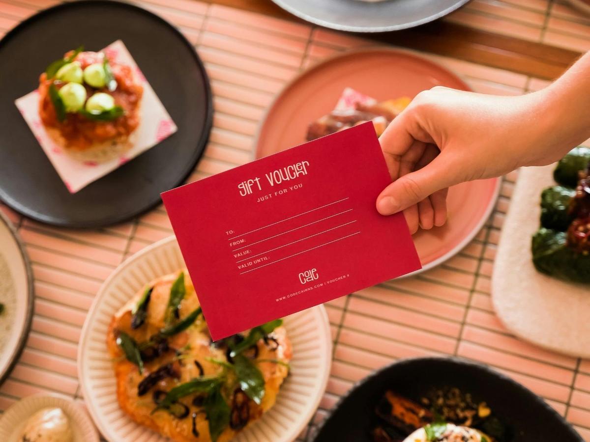 A restaurant voucher is prominently displayed in front of an array of share plates on a table.