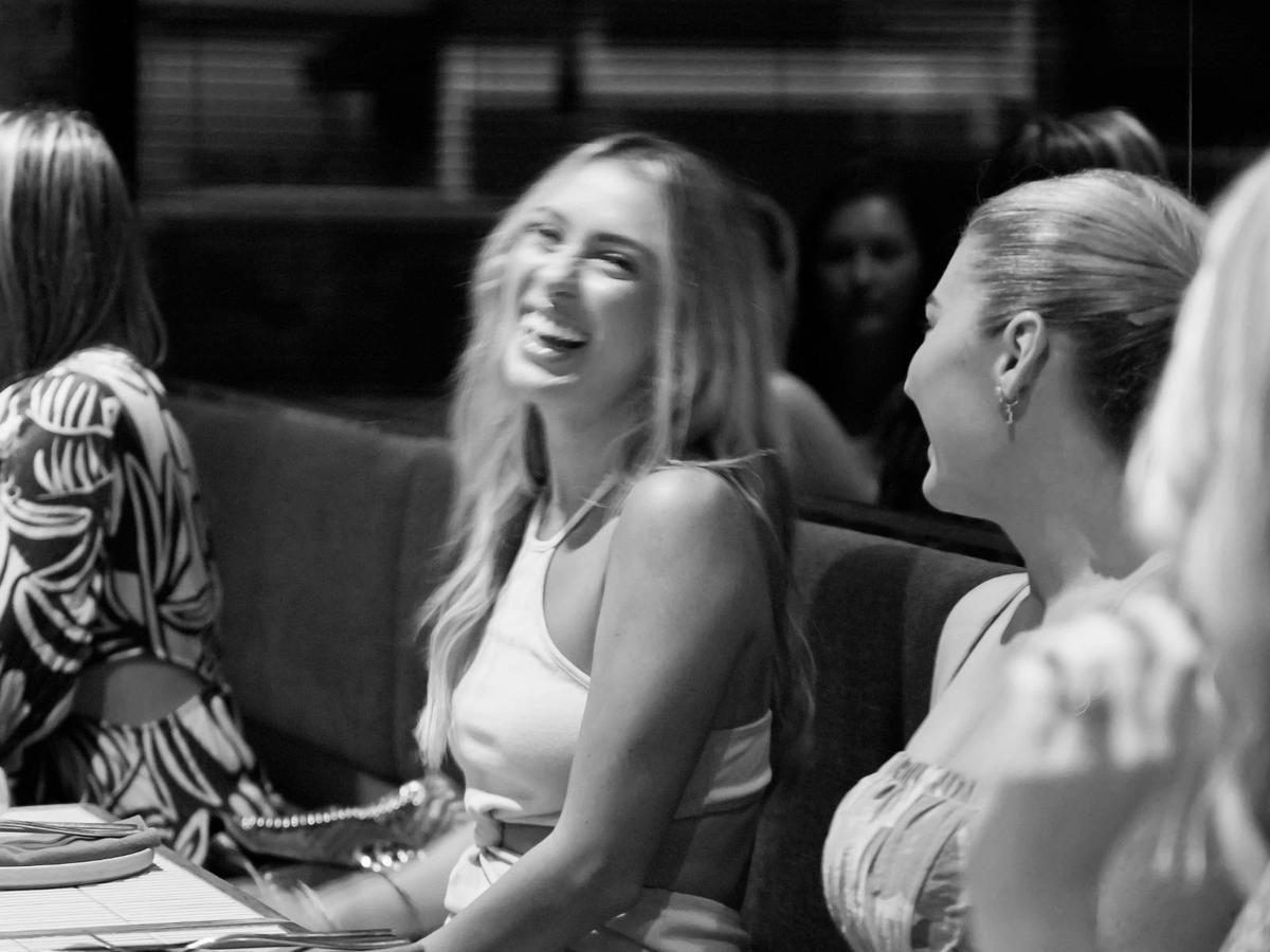 Two women are seated in restaurant, laughing and enjoying their time together.