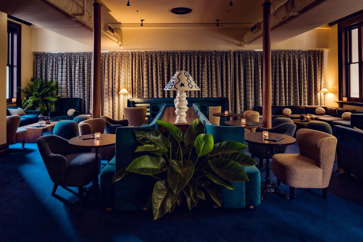 A lounge and bar, with blue furniture and plants