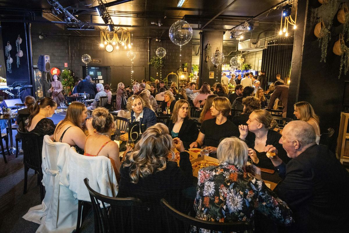 Vibrant room filled with people sitting at tables with clear balloons wrapped in fairy lights