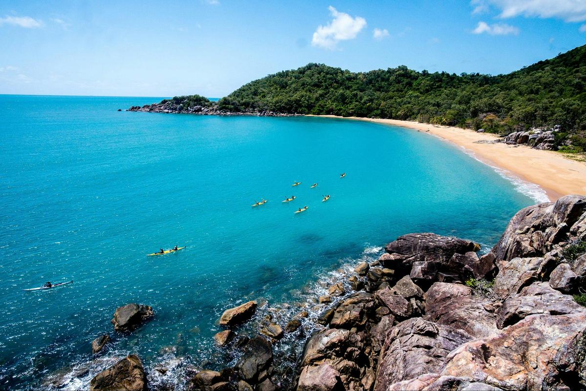 A group of Sea Kayakers paddle across Orchid Bay at the Northern tip of Hinchinbrook Island