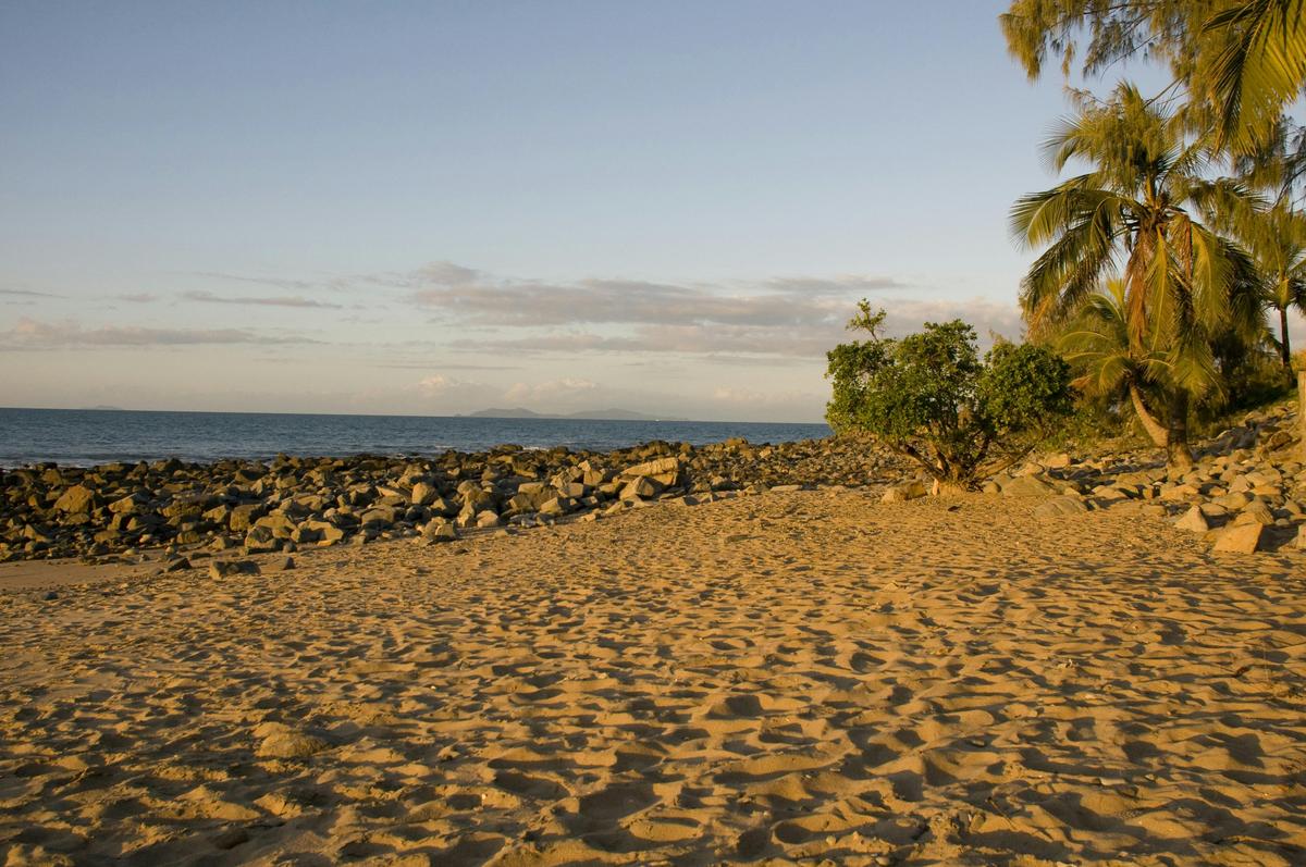 Dolphin Heads sunset over looking the water sand in the forground with rocks and palms in the back.