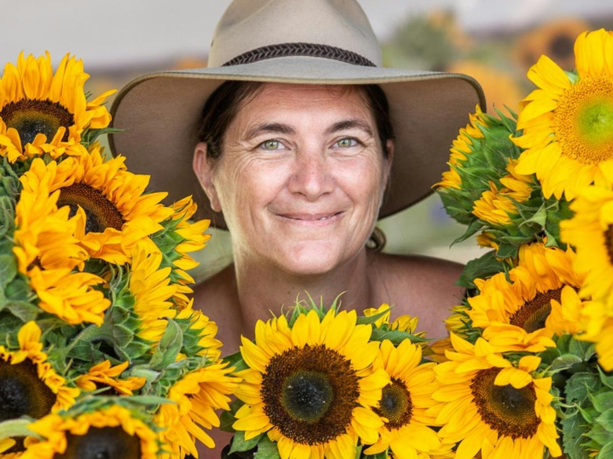 Smiling female farmer surrounded by sunflowers