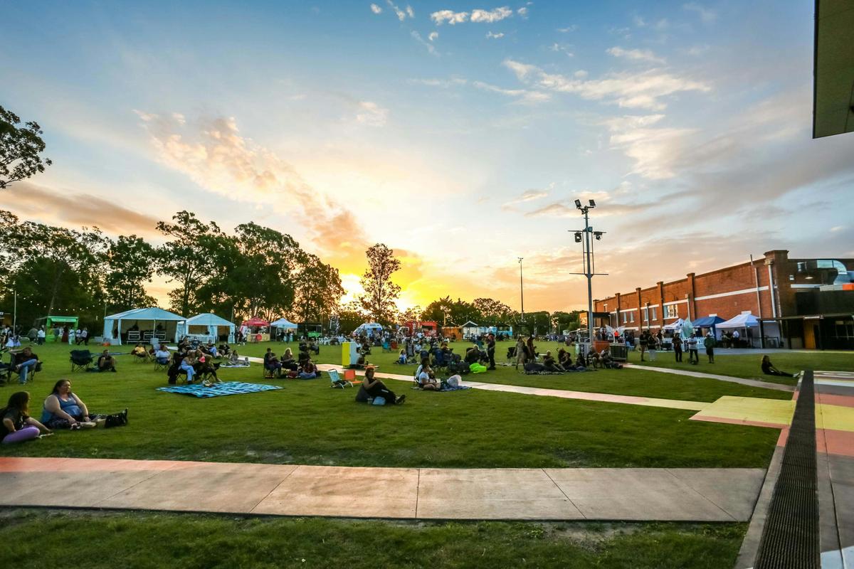Audiences relax on the green waiting for the show to begin on the big stage.