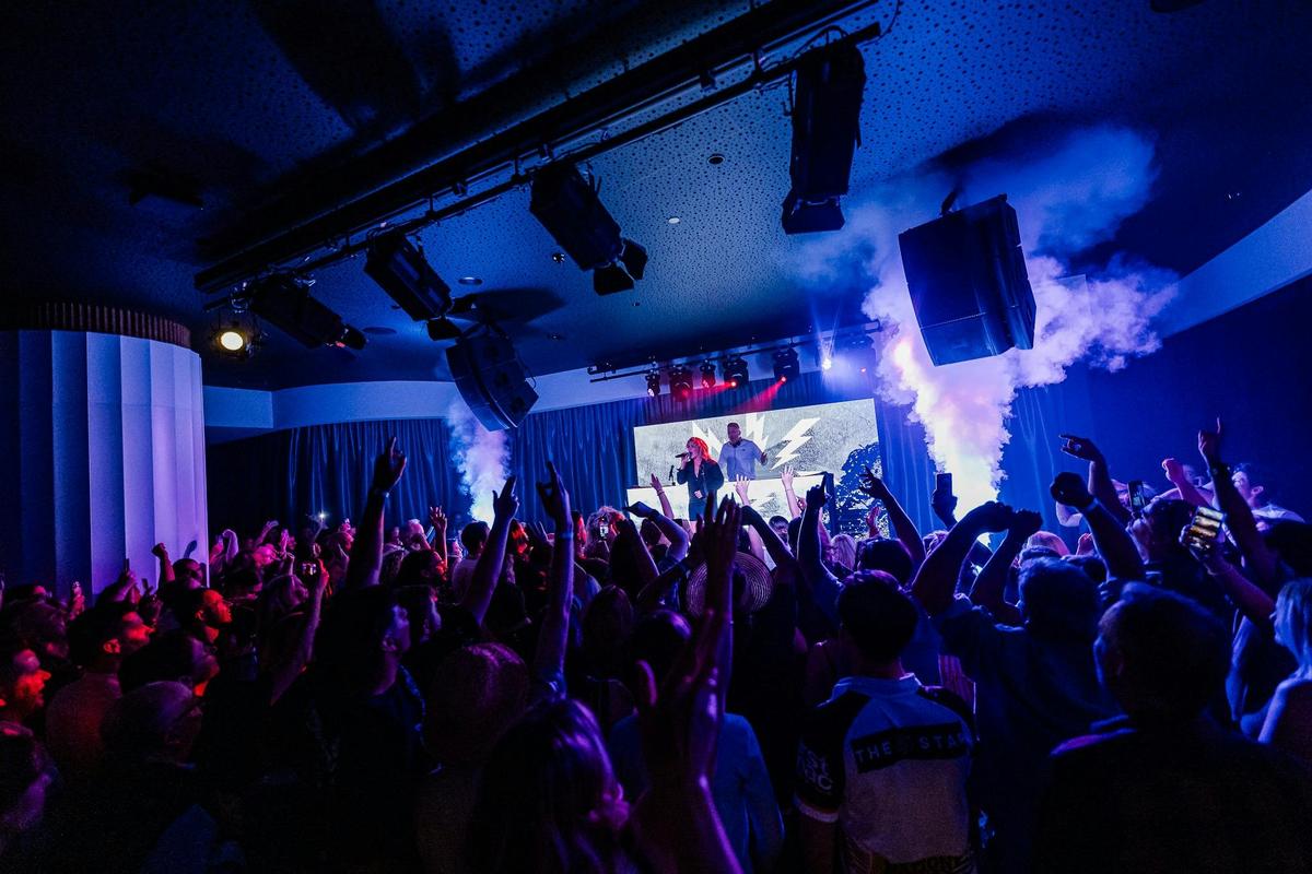 people dancing in front a stage where a woman is performing