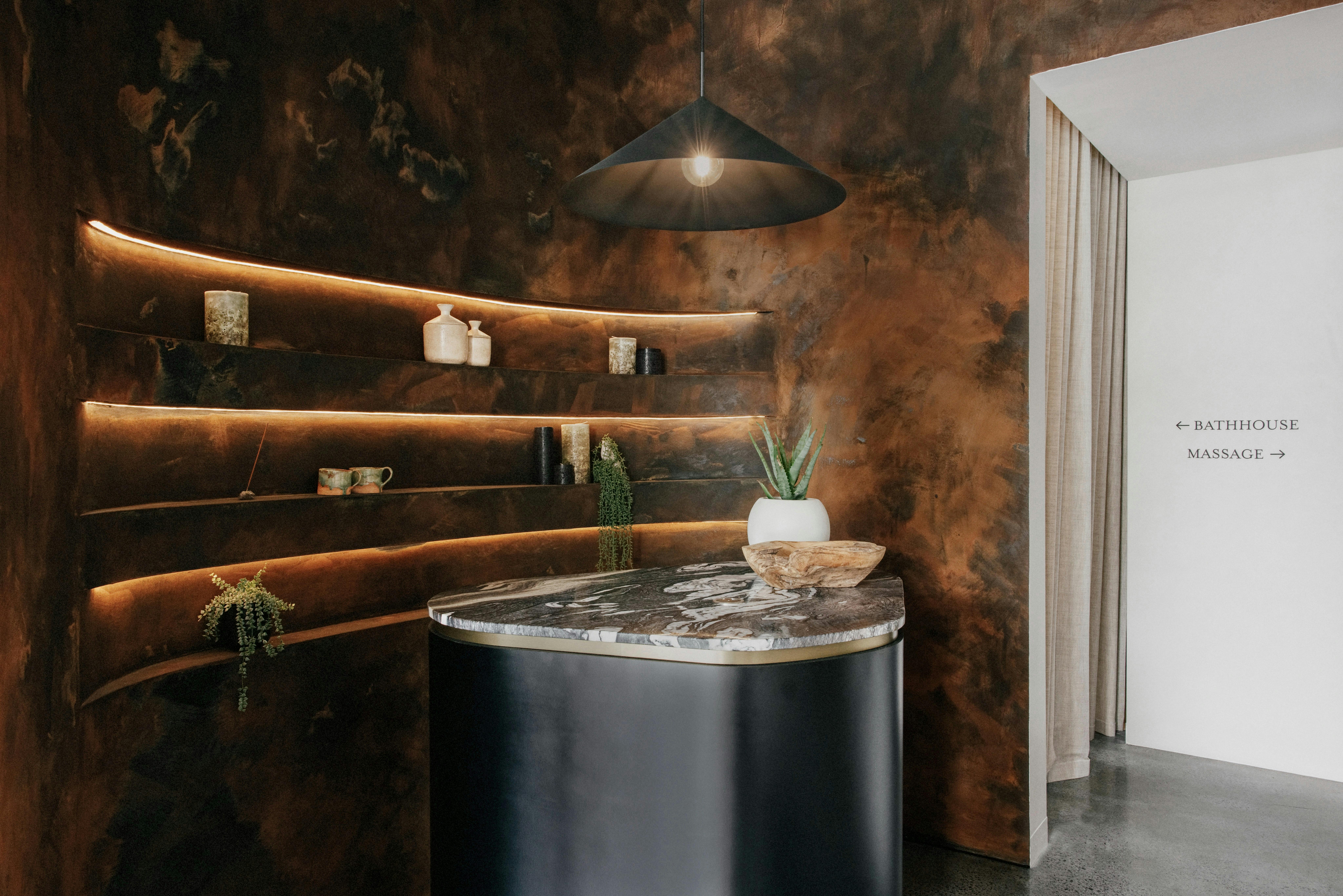 The reception desk and curved rust wall at Navia Bathhouse.