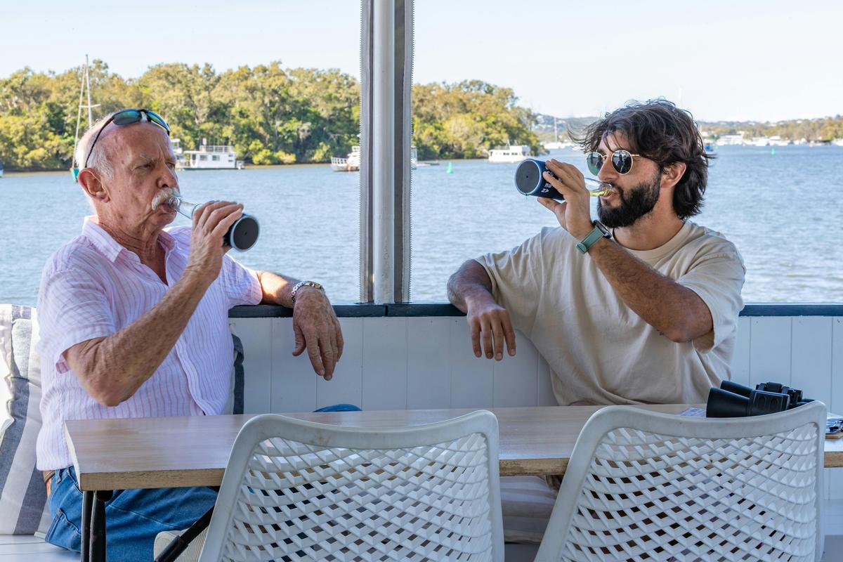 Two people enjoying seafood whilst outside sipping on cocktails on a boat