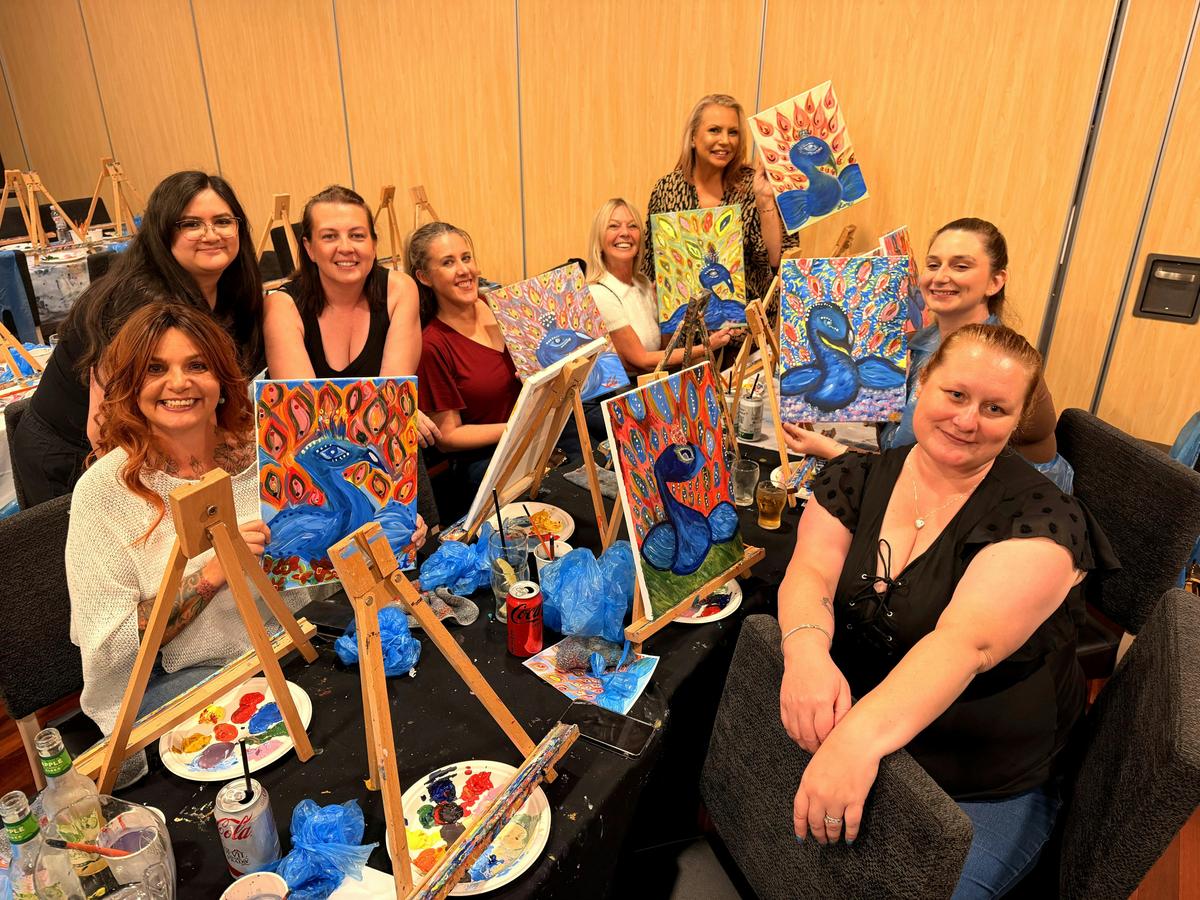 Paint Juicy guests painting at a table of canvases and palettes during a mobile paint and sip sessio