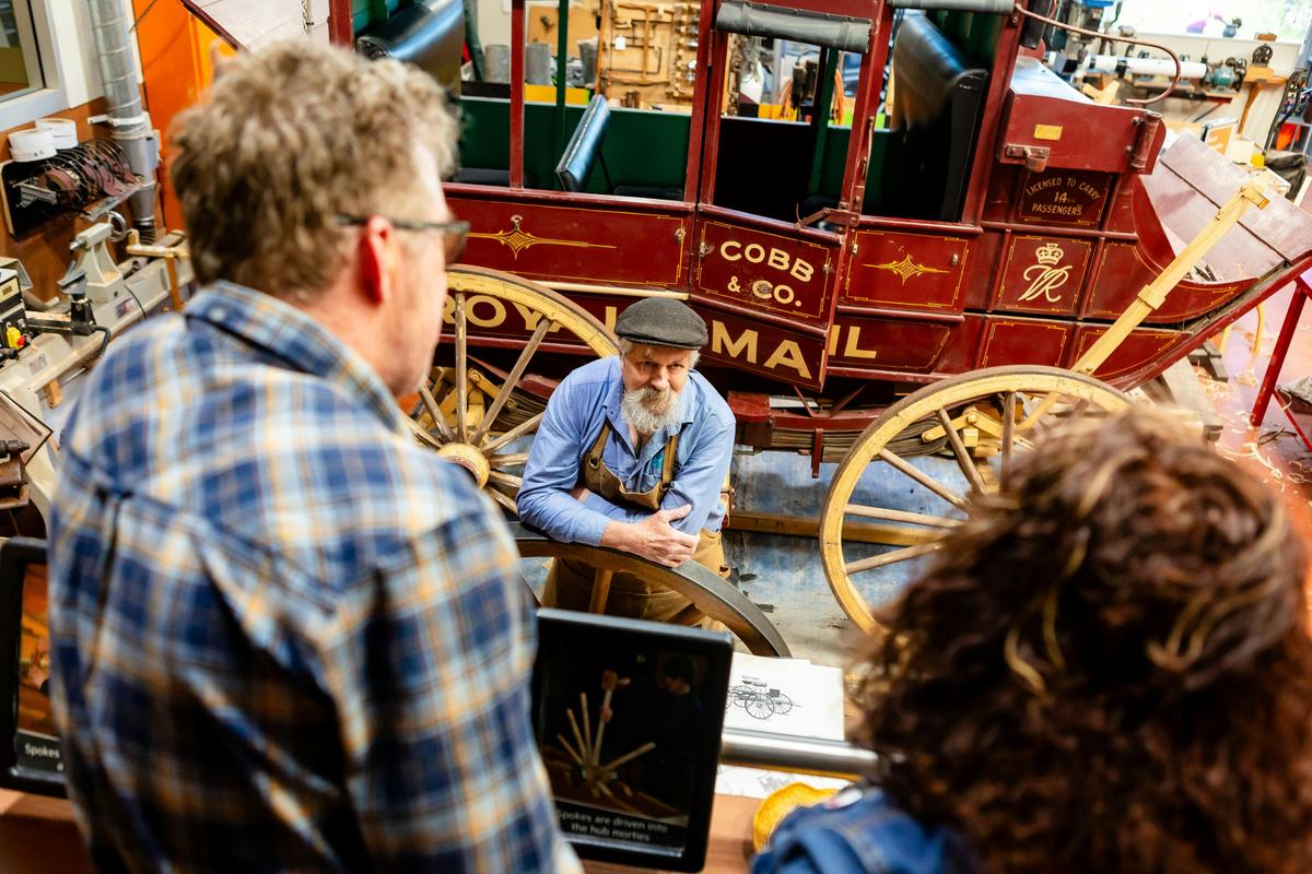 Factory worker talking to visitors with Cobb & Co coach in the background