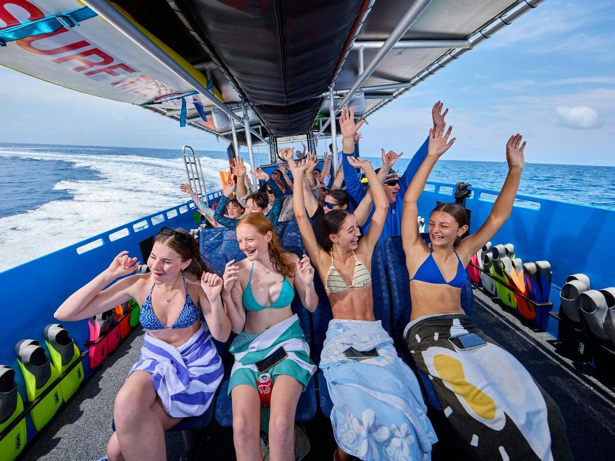 Guests experiencing a fast boat ride with hands in the air out of enjoyment