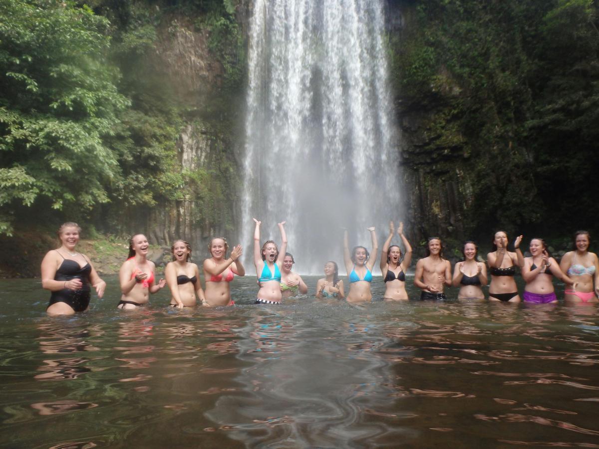 Student group swimming under waterfalls