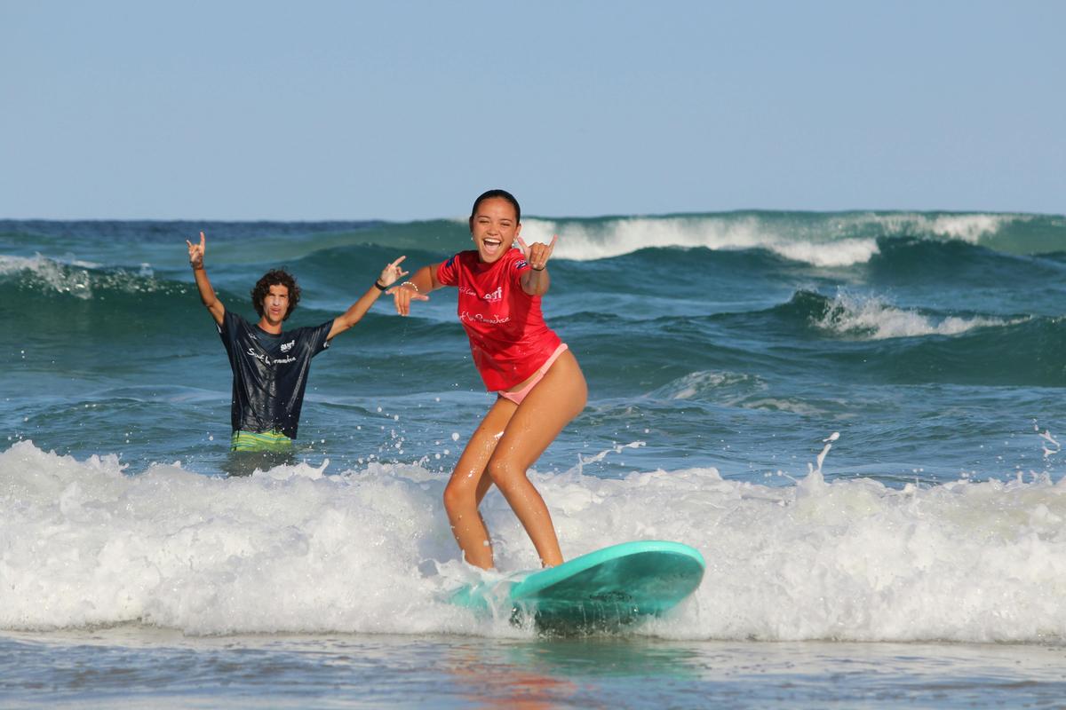 Coach encougeraging girl having fun in surf lesson