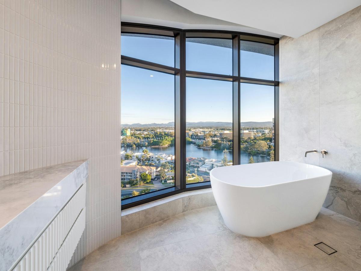 The master ensuite holds a freestanding bath in a corner of glass.