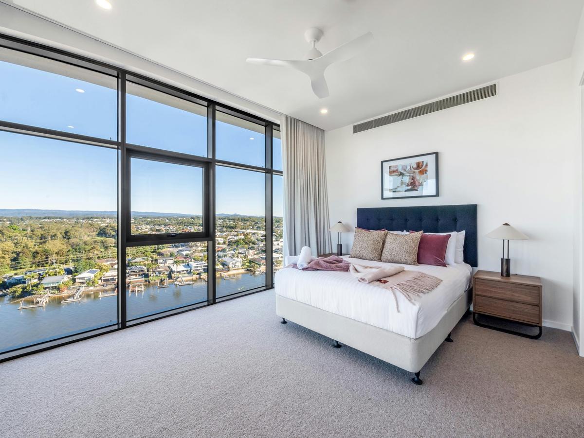 A queen bedroom wrapped in full-height glass above the water.