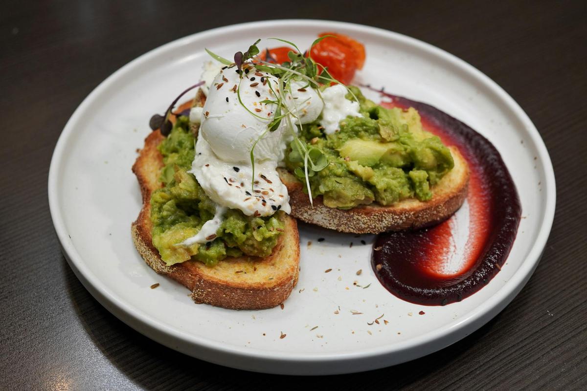 A breakfast order with smashed avocado and poached eggs on toast
