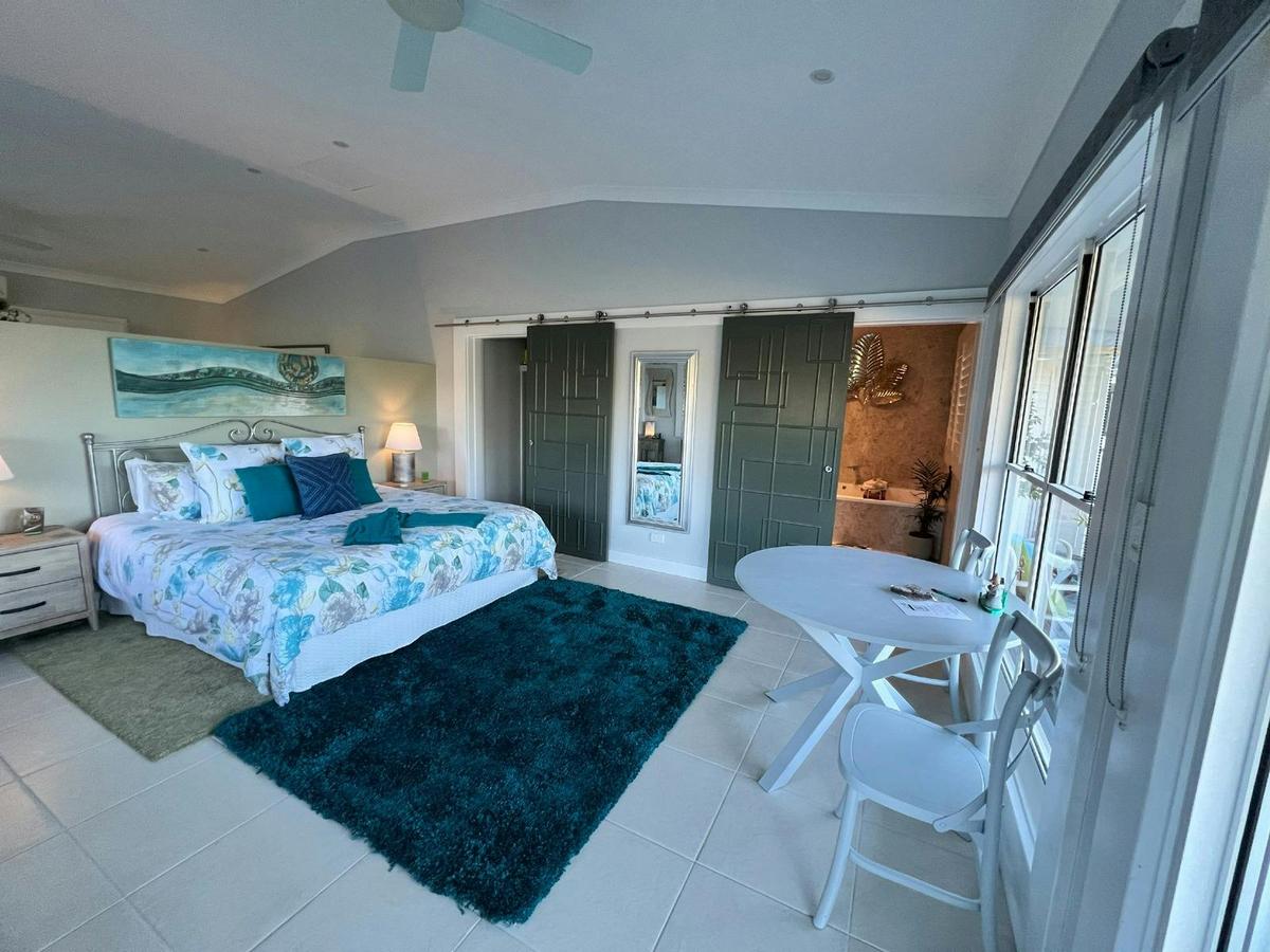 Rainforest Retreat bedroom with king bed, timber doors, and veranda overlooking lush rainforest.