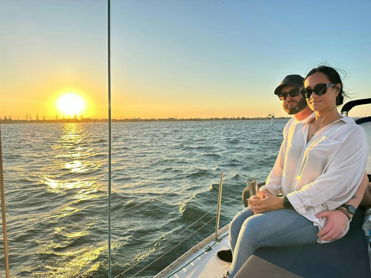 Couple enjoying a shared sunset sail with Sun Sailing