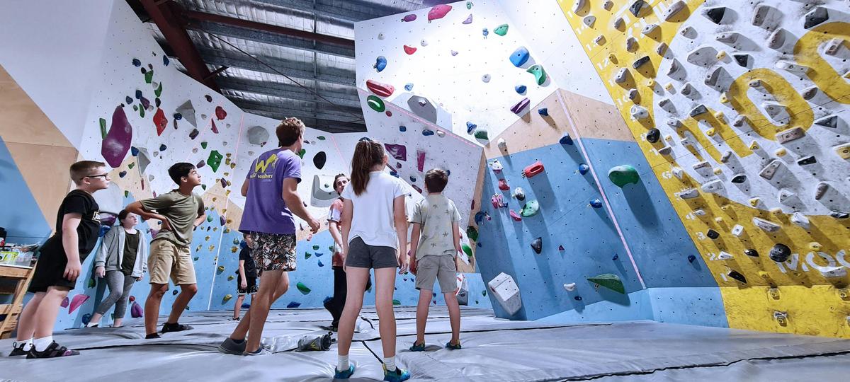 YouthFam climbing lessons for kids.  Discussing beta for a difficulty route with their coach.