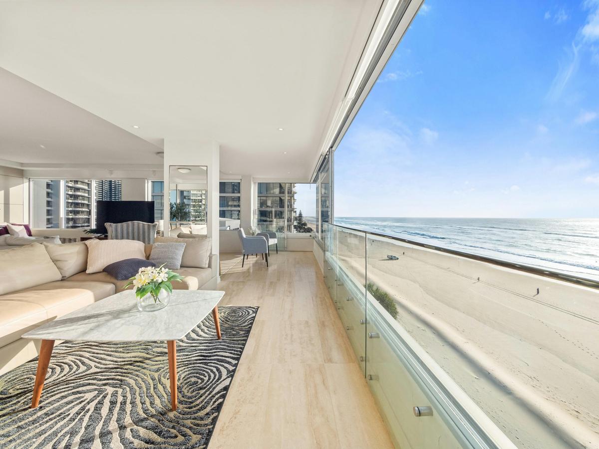 The living room glass slides open to the sea, the sand directly below.
