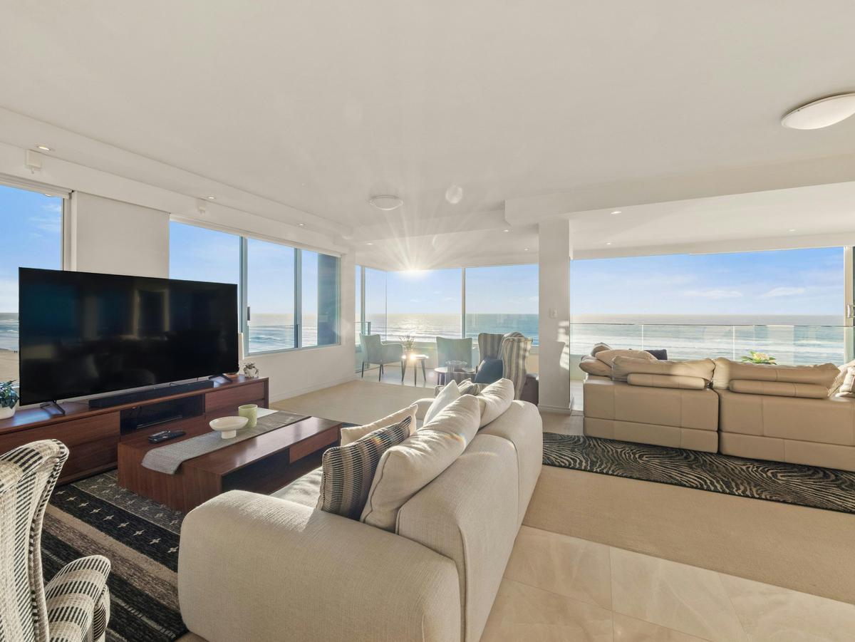 The living room opens the full width to the sea, the horizon behind the glass.