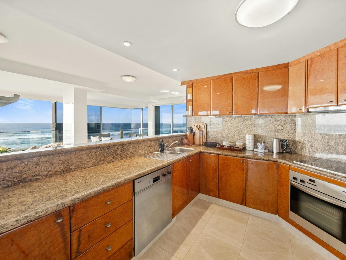 The kitchen in granite and timber, the sea over the sink.