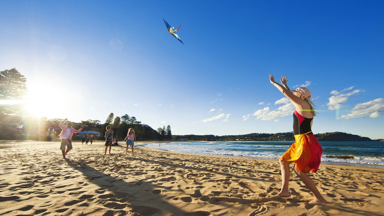 Family flying a kite on Avoca Beach, Central Coast