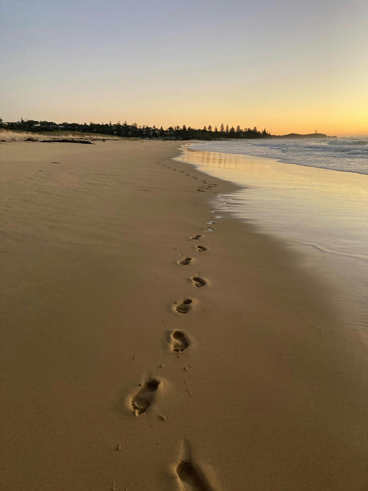 Barefoot footprints leading along the pristine beach track towards Tuross Head.
