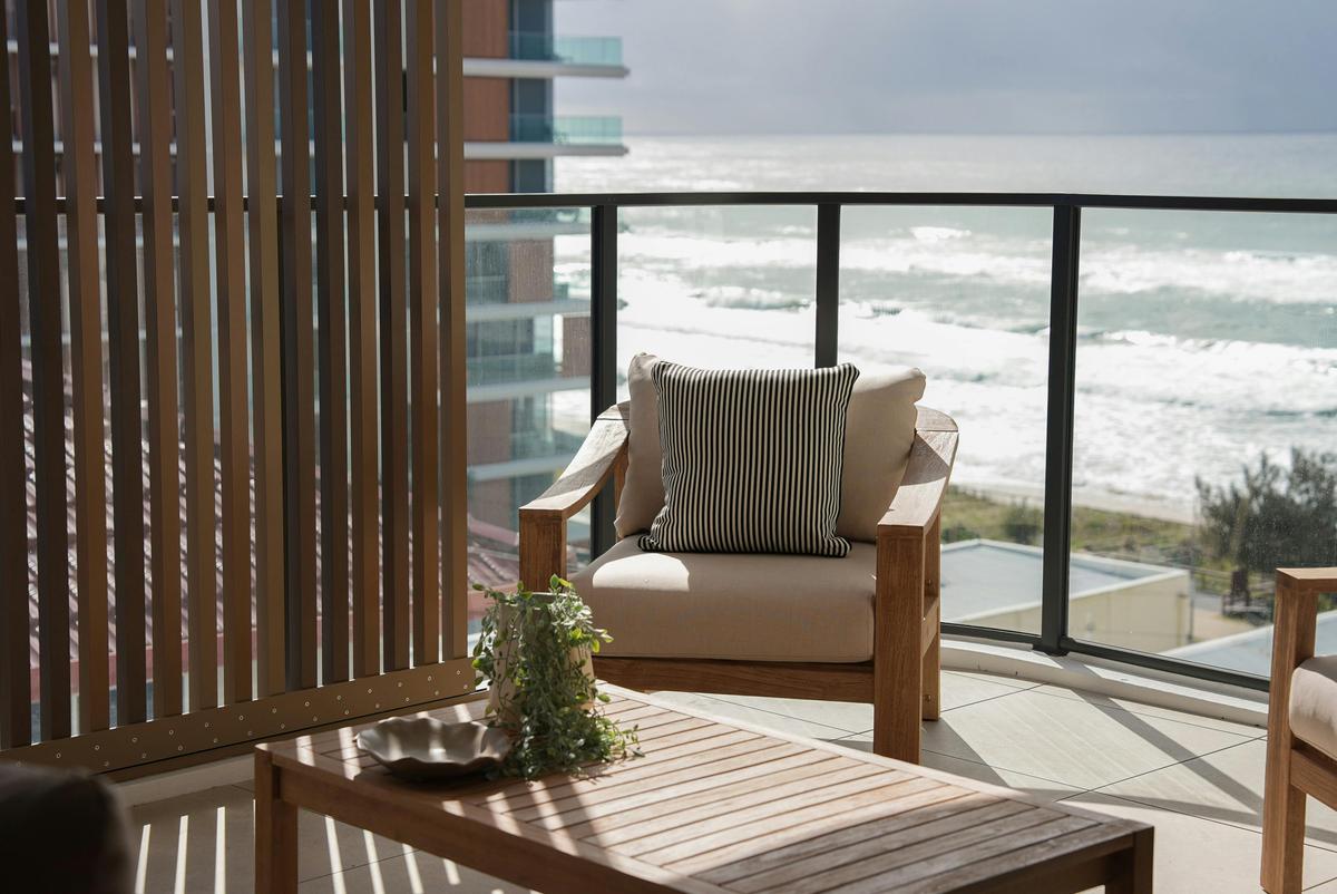 Curved terrace above the sand, timber screens filtering the afternoon sun.