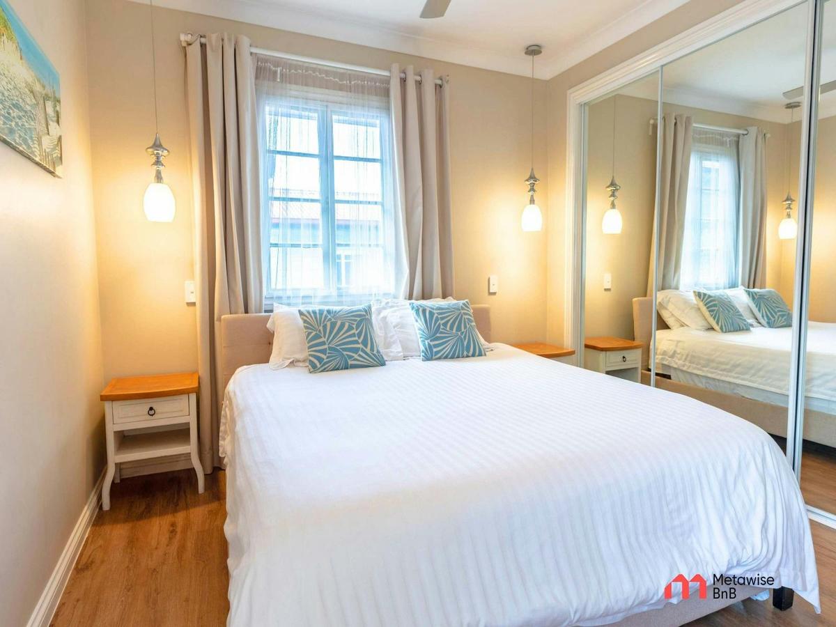 Spacious bedroom featuring a king-sized bed, mirrored built-in wardrobe, and bedside lighting.