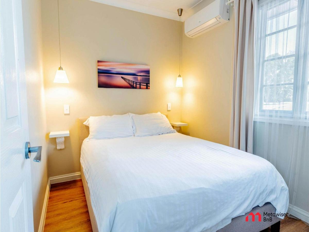 Bedroom with a queen-sized bed, bedside lamps, wall artwork, and air conditioning.