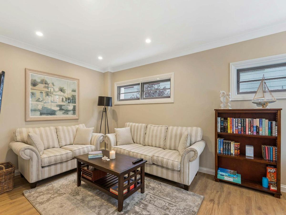 Formal living room with two cream sofas, coffee table, bookshelf, and wall artwork.