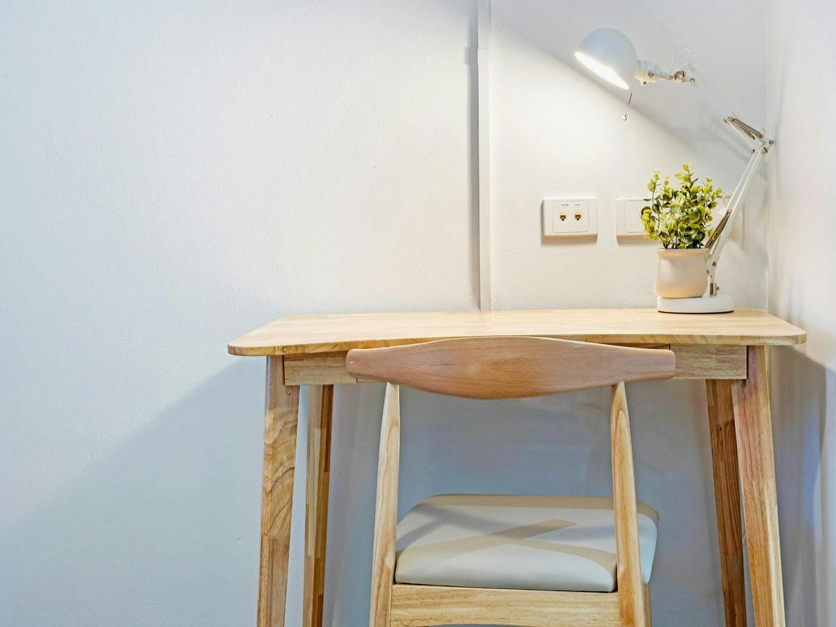Compact wooden work desk with lamp and decorative plant.