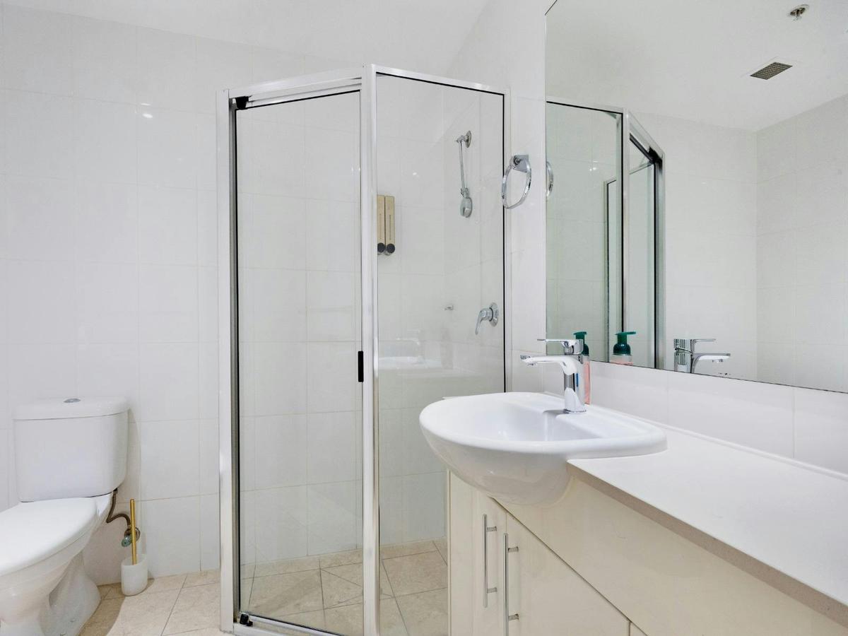 Modern bathroom with glass shower enclosure, vanity with mirror, and toilet.