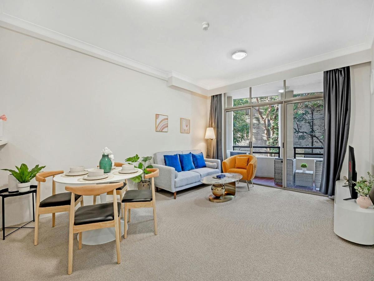 Spacious living area with dining table, lounge seating, and sliding door access to the balcony.